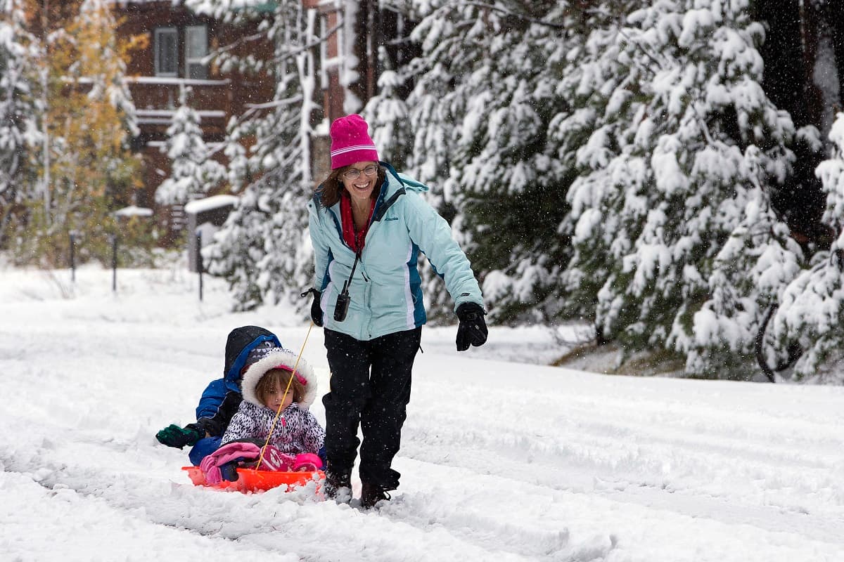 Una madre y sus hijas juegan con la nieve en Serene Lakes, CA.