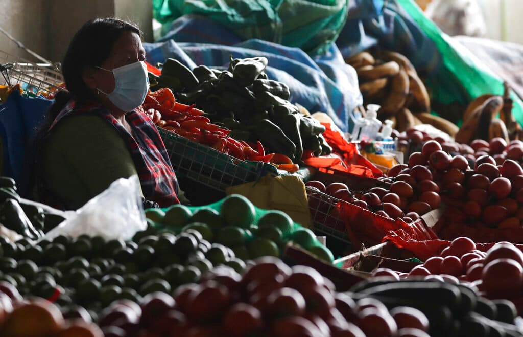 Una vendedora espera a los clientes en un puesto de mercado con la cara cubierta para protegerse del COVID-19 en el centro de Quito, Ecuador, el 17 de marzo de 2020.