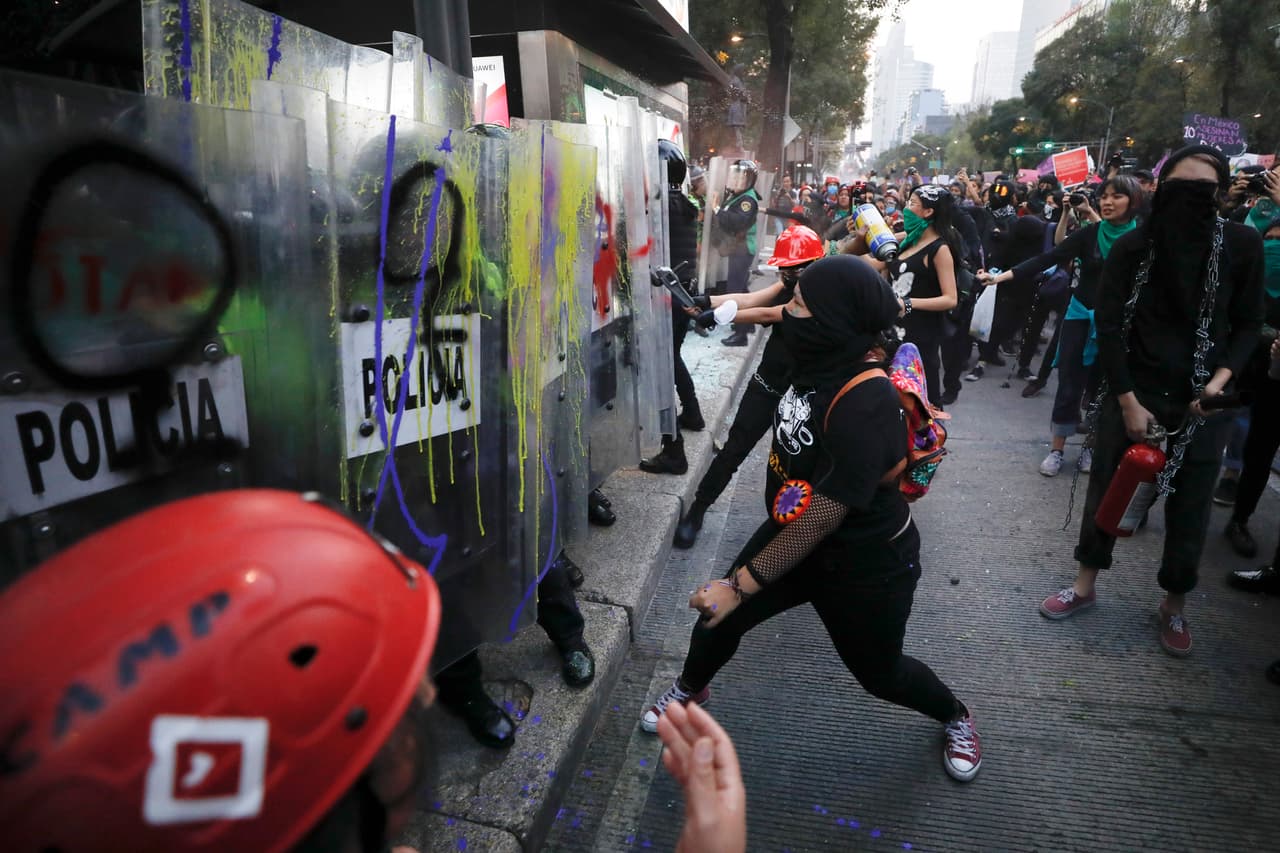 <b>MÉXICO:</b> Mujeres pintan los escudos de la policía antidisturbios durante una marcha en protesta por la violencia contra las mujeres en la Ciudad de México.