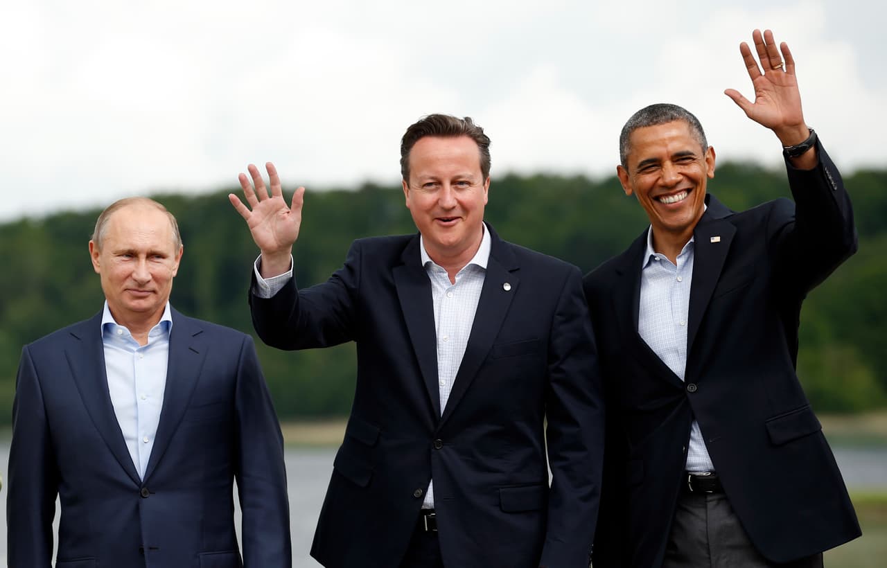 Barack Obama saluda mientras Vladimir Putin se mantiene firme, durante la foto oficial del G8 realizado en Enniskillen, Reino Unido. Entre los dos mandatarios el anfitrión David Cameron. 18 de junio de 2013.