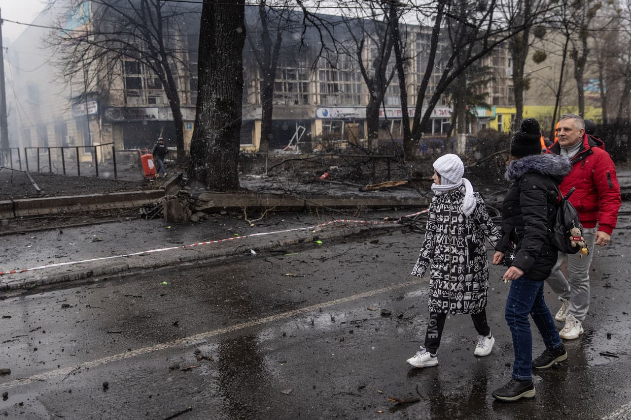 Residentes de Kiev caminan frente a un edifico dañanado por los ataques de Rusia el 1 de marzo. Fuertes explosiones han sacudido a la capital por quinto día consecutivo. Según Ucrania, algunas corresponden a los proyectiles antiaéreos ucranianos que han interceptado los misiles de Rusia.