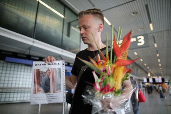 El holandés Arthur Laumann porta una ofrenda floral junto con la fotografía de su amigo Wayan Sujana, uno de los pasajeros del avión.