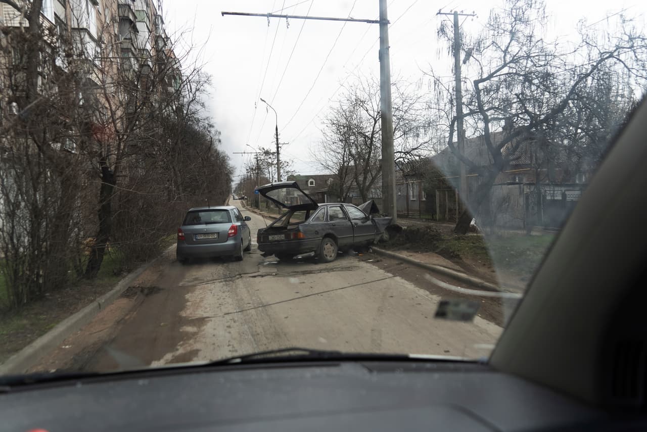 A car escaping from shelling drives past a crashed vehicle in Mariupol, Ukraine, Friday, March 4, 2022 (AP Photo/Mstyslav Chernov)