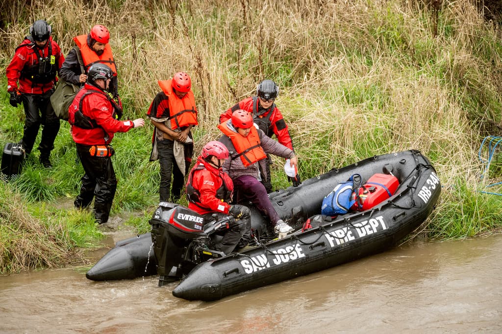 Trabajadores de búsqueda y rescate evacuan a hombres de un campamento para personas sin hogar que quedó rodeado por las inundaciones del río Guadalupe el domingo 4 de febrero de 2024 en San José, California (Foto AP/Noah Berger).
