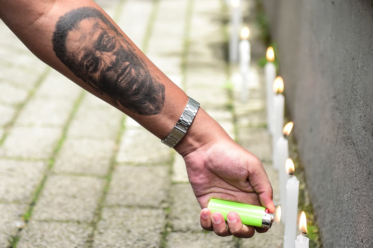 Una persona con un tatuaje de Pelé enciende una vela mientras los aficionados celebran una vigilia en apoyo de la leyenda del fútbol que pasó un mes hospitalizado debido a una infección respiratoria en medio de los tratamientos de cáncer de colon en el Hospital Israelita Albert Einstein.