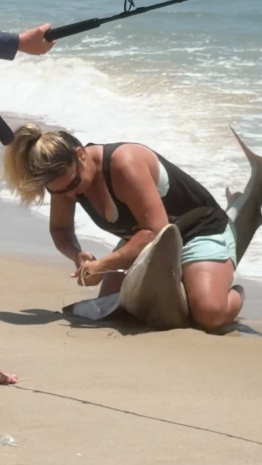 Una mujer libera a un tiburón de un anzuelo