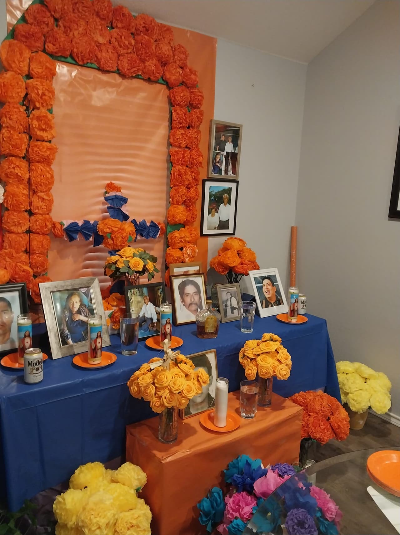 Las flores no faltan en este bello altar de Mary Magdaleno con las fotos en grande de su familia y veladoras de santos.