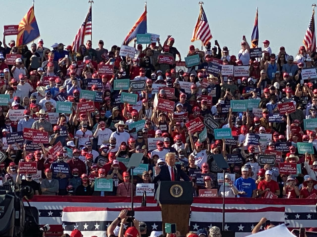 Atrás de Trump varias personas sostenían letreros de Latinos por Trump, la mayoría blancos.