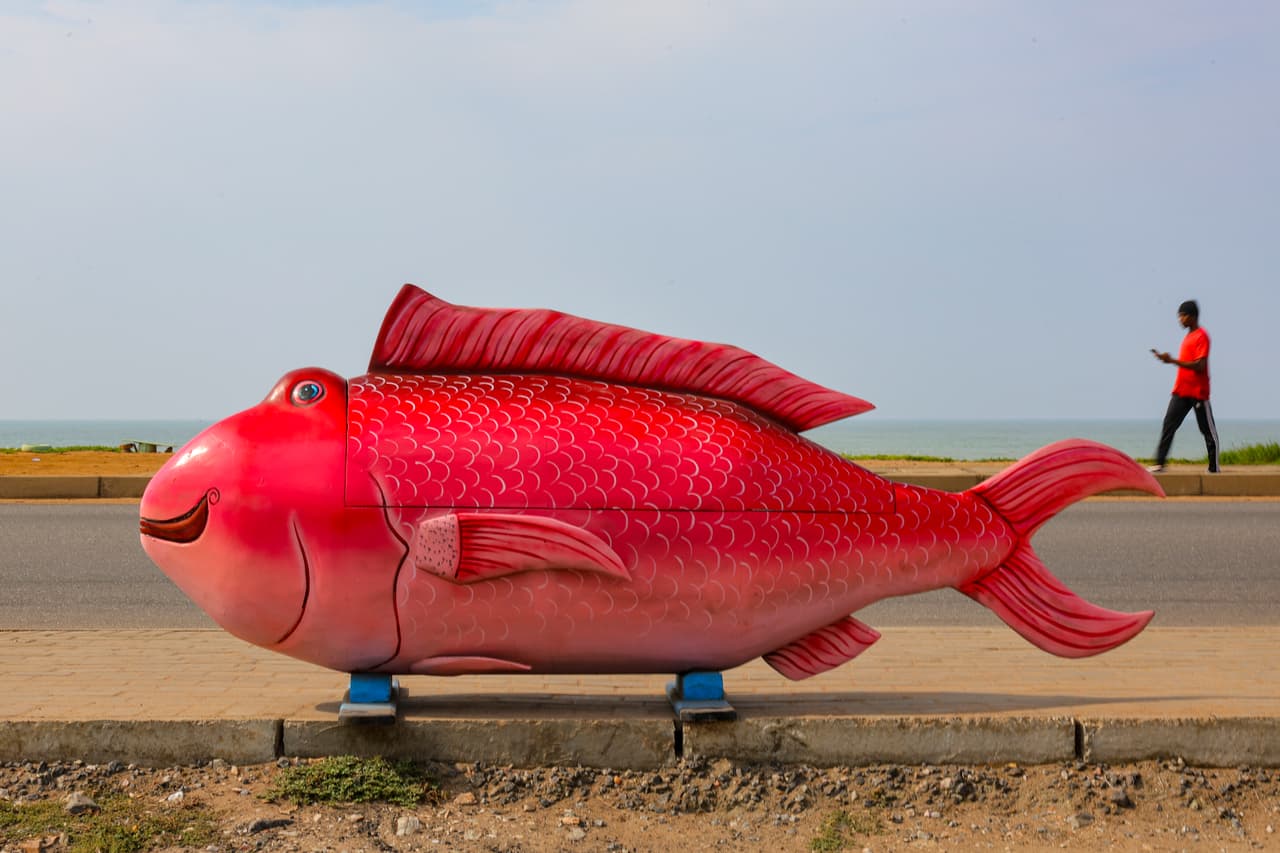 <b>Un pez gigante junto a la carretera: </b>Una de las creaciones de Eric Kpakpo Adotey permanece expuesta al borde de una carretera en La, Accra. El ataúd, tallado con forma de pez, parece una escultura a plena vista y muestra el carácter llamativo de esta tradición funeraria.