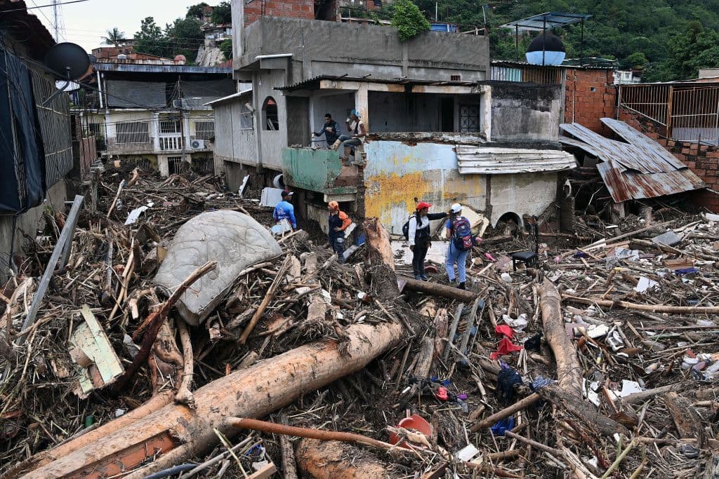 Equipos de rescate y familiares buscan entre los escombros de casas arrastradas por la crecida de un arroyo.