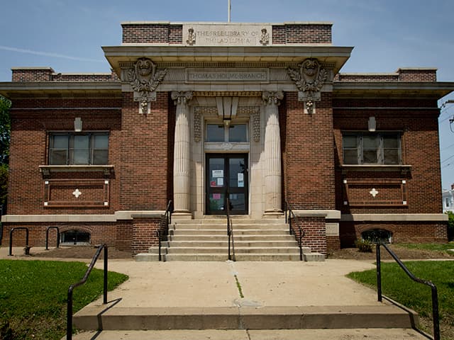 <b>Holmesburg Library</b>
<br>7810 Frankford Avenue
<br>Philadelphia, PA 19136-3013
<br>215-685-8756
<br>
<br>Holmesburg Branch se fundó en 1867 como Holmesburg Reading Room and Library Association, una biblioteca por suscripción. En 1880, se transfirió a los administradores de la Academia de Dublín Inferior y se la denominó Biblioteca gratuita Thomas Holmes. En 1899, un acuerdo entre los fideicomisarios de la academia y la 
<a href="https://libwww.freelibrary.org/locations/holmesburg-library" target="_blank">Biblioteca Libre</a> de Filadelfia estableció la sucursal de Thomas Holme, que abrió en 1900 en Atheneum, 8000 Frankford Ave. En 1906, los fideicomisarios de la Academia de Lower Dublin donaron un terreno y el filántropo Andrew Carnegie donó fondos para una nueva biblioteca, que abrió el 26 de junio de 1907. Fue renovada en 1998. 
<br>
