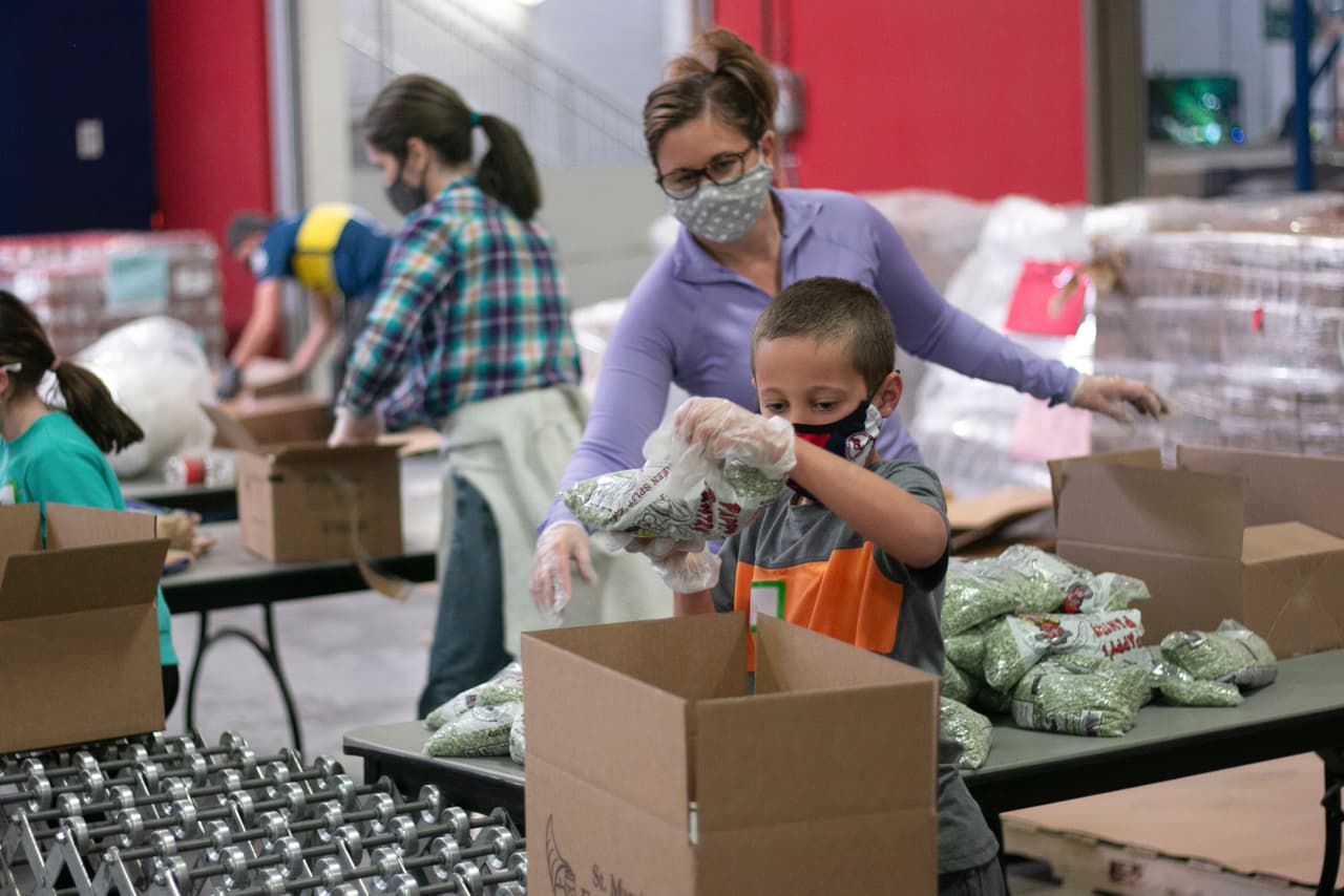 Erin Pfeifer, de 40 años, y su hijo de ocho años, Dylan, trabajan como voluntarios en un banco de alimentos de Phoenix (Arizona). La pandemia dificultó la labor de las organizaciones
<b>que reparten alimentos</b> entre niños al cerrar los centros escolares. La cantidad de comidas gratis para niños cuyas familias satisfacen ciertos requisitos de ingresos cayó pronunciadamente. Entre marzo y noviembre de 2020 se sirvieron 1,650 millones de desayunos menos que entre marzo y noviembre de 2019, lo que representa una merma del 30%.
