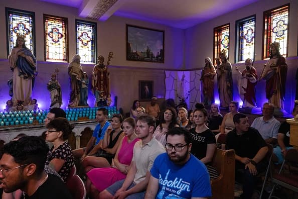 Los fieles sentados en los bancos de la iglesia rodeados de imágenes de santos.