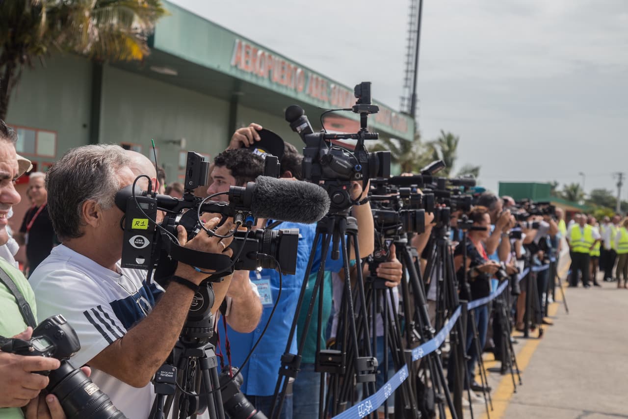 Una fila de camarógrafos y fotógrafos toman imágenes de los pasajeros al descender del avión de JetBlue en Santa Clara. El evento generó una cobertura mediática local inusitada en Cuba, reuniendo tanto a medios nacionales como a todas las agencias de prensa y corresponsales internacionales.