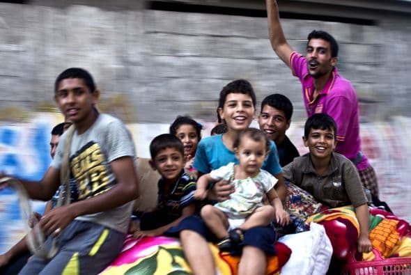 Tras el fin de la guerra, jovenes y niños pasean en un carruaje jalado por caballos mientas se dirigen con sus pertenencias a sus casas.  
