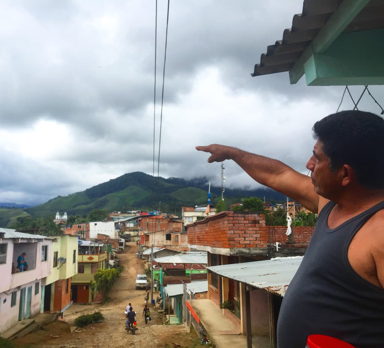 Adolfo López points to the could-covered hilltop where the FARC's disarmament camp is situated. Photo by Maximo Anderson.