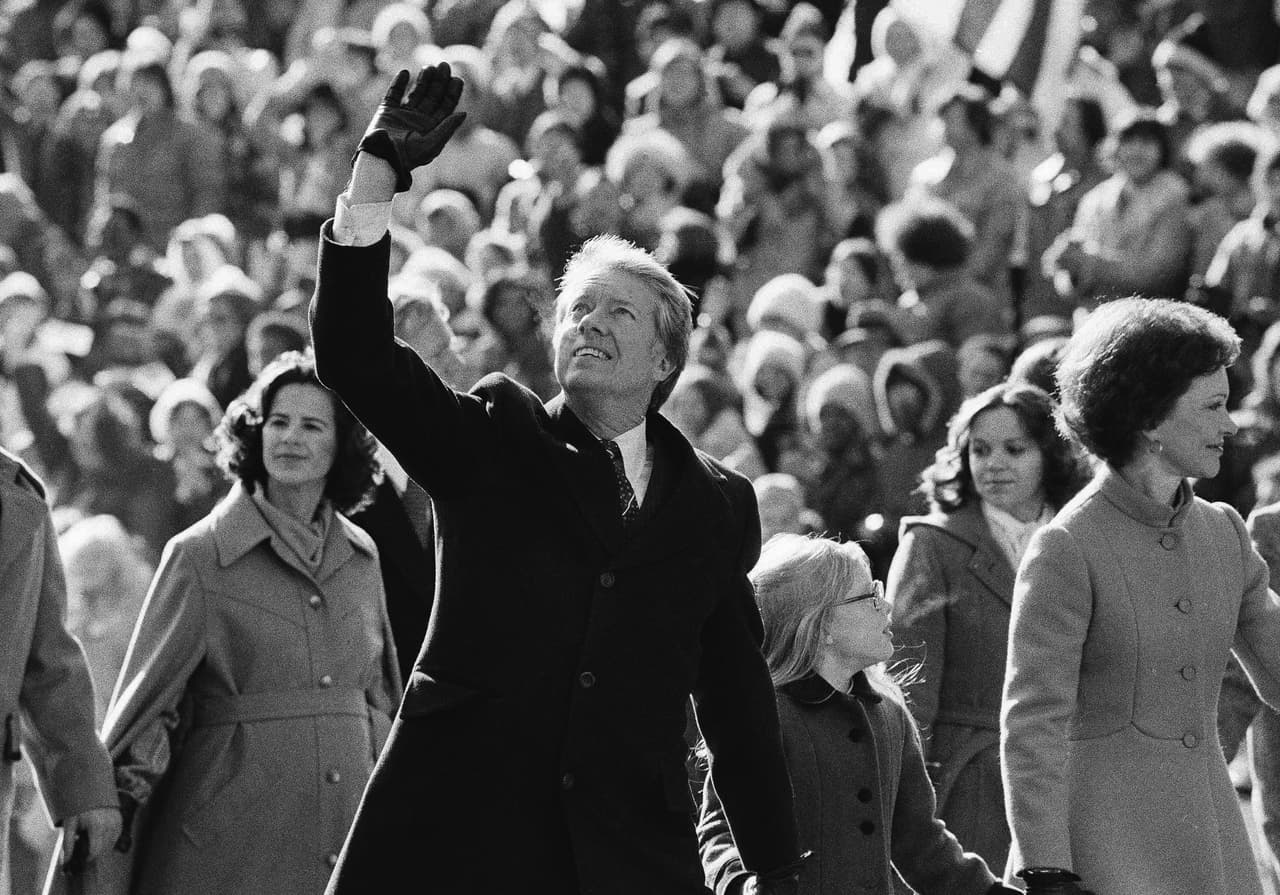 Jimmy Carter saluda a la multitud mientras camina con su esposa Rosalynn y su hija Amy por la Avenida Pennsylvania desde el Capitolio hasta la Casa Blanca después de su investidura, el 20 de enero de 1977.