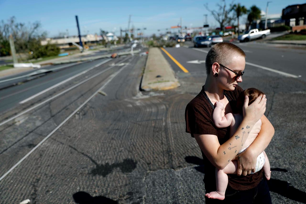 Kylie Strampe con su hija de cuatro meses, Lola. Observa los daños causados por el huracán Michael después de resistir la tormenta en Callaway, Florida.