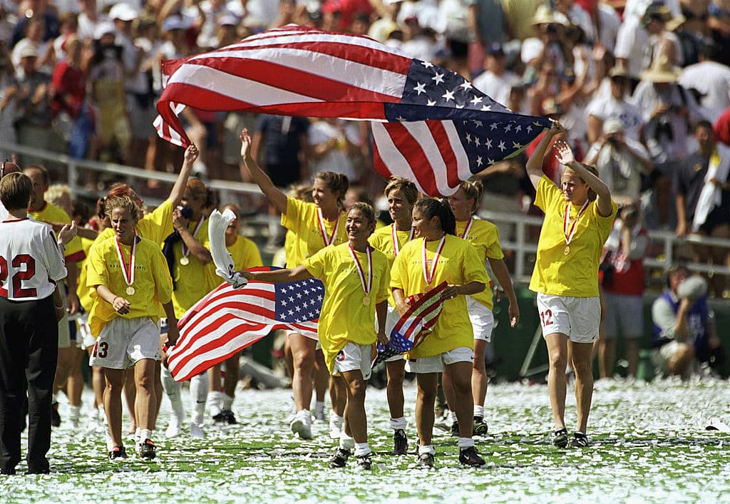 El Team USA agita banderas en el campo de juego con motivo de la celebración del campeonato en la edición de 1999 en el Mundial Femenino, luego de vencer 5-4 a China en el Rose Bowl el 10 de julio de 1999 en Pasadena, California.