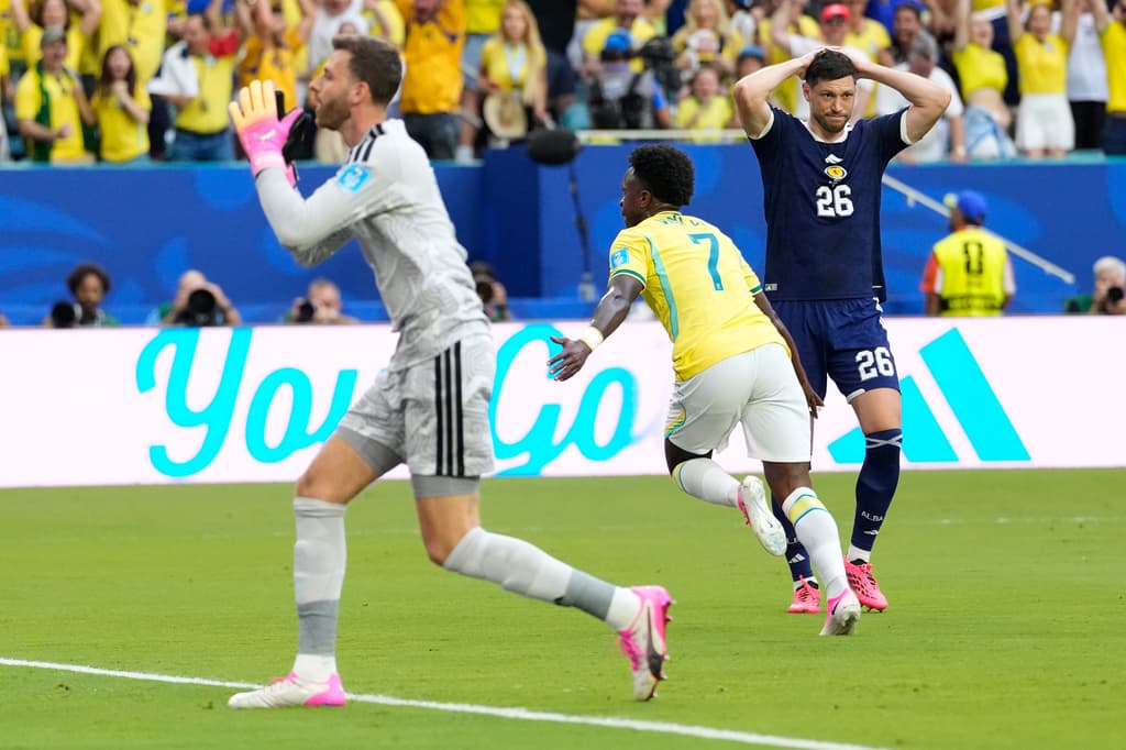 El brasileño Vinicius Junior (7) celebra tras marcar el primer gol de su equipo, mientras el portero de Escocia, Angus Gunn (1), y Scott McKenna (26) reaccionan.