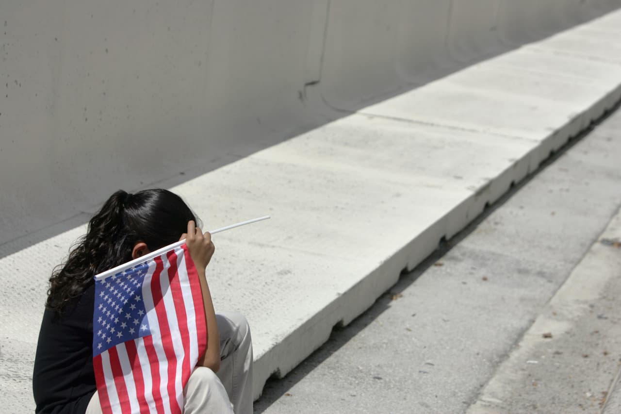 Miami, UNITED STATES: US-born Stephanie crouches down while holding a US flag in front in front of the US federal courthouse in Miami, Florida, 04 October 2006. Stephanie's mother, Marta, is one of some 12 million illegal immigrants living in the US, according to estimates by the PEW Hispanic center in the US. Lawyers representing some 60 mostly latin children presented a motion before the court in an effort to stop the deportation of the children's parents who reside in the US illegally. The lawyers argue that the basic human rights of the children would be violated if their parents are deported. AFP PHOTO/ROBERTO SCHMIDT (Photo credit should read ROBERTO SCHMIDT/AFP/Getty Images)