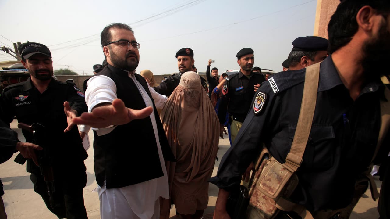 Un policía escolta a Sharbat Gula -cubierta por un burka- a su llegada a la corte de Peshawar el 4 de noviembre de 2016.