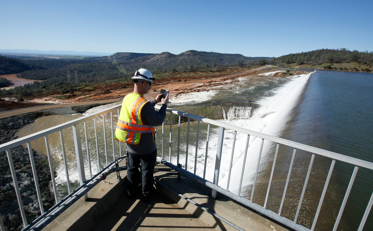Jason Newton, del Departamento de Recursos Hídricos, toma una fotografía del agua que atraviesa el vertedero de emergencia en la presa de Oroville.