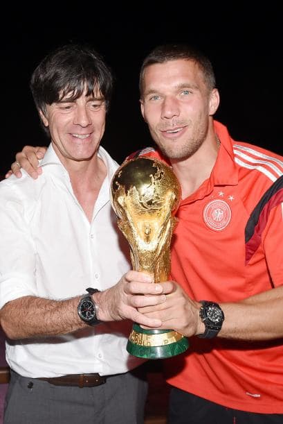 El técnico Joachim Löw junto a Lukas Podolski con el trofeo.