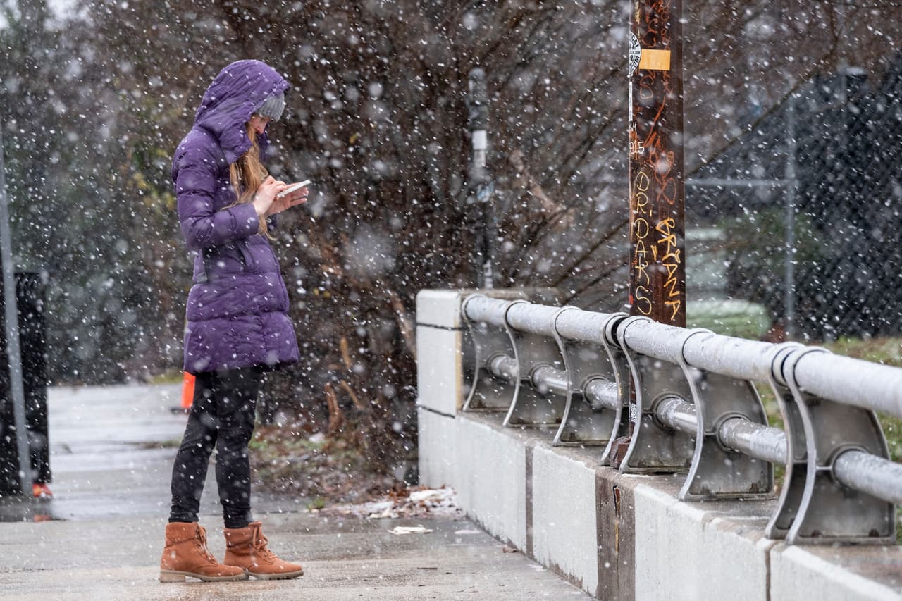 Bridget Step mira su teléfono bajo la nieve que cae en 
<b>Atlanta, Georgia</b>. El estado sureño fue otro de los afectados por la enorme tormenta invernal. A las 2 de la tarde (ET) de este domingo, unos 278,000 clientes se encontraban sin electricidad. De ellos, unos 58,000 estaban en Georgia. Hacia las 8 de la noche (ET), 27,000 continuaban sin luz, de acuerdo con el sitio poweroutage.us.