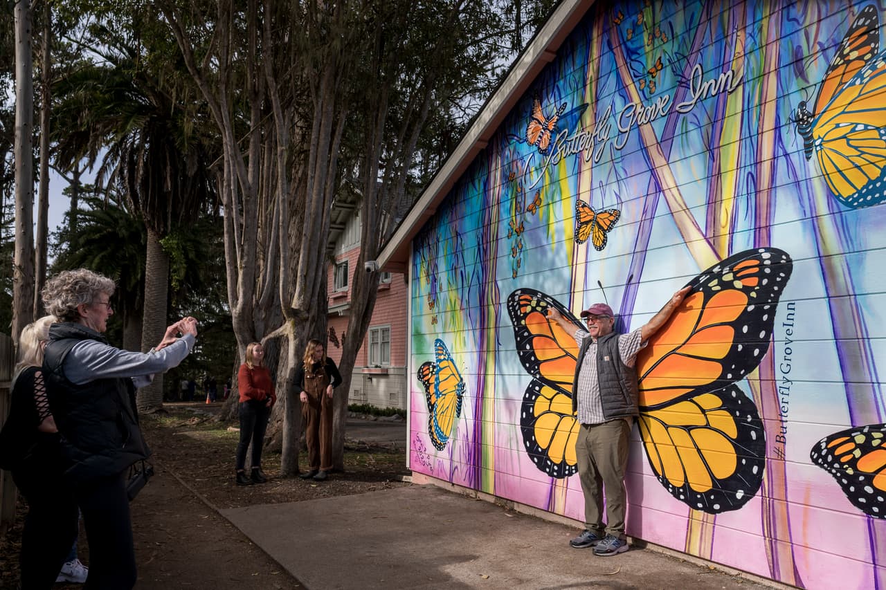 Leslee Russell toma una fotografía de su esposo, Dave Russell, frente a un mural afuera del Butterfly Grove Inn, situado cerca del Monarch Grove Sanctuary en Pacific Grove, California.