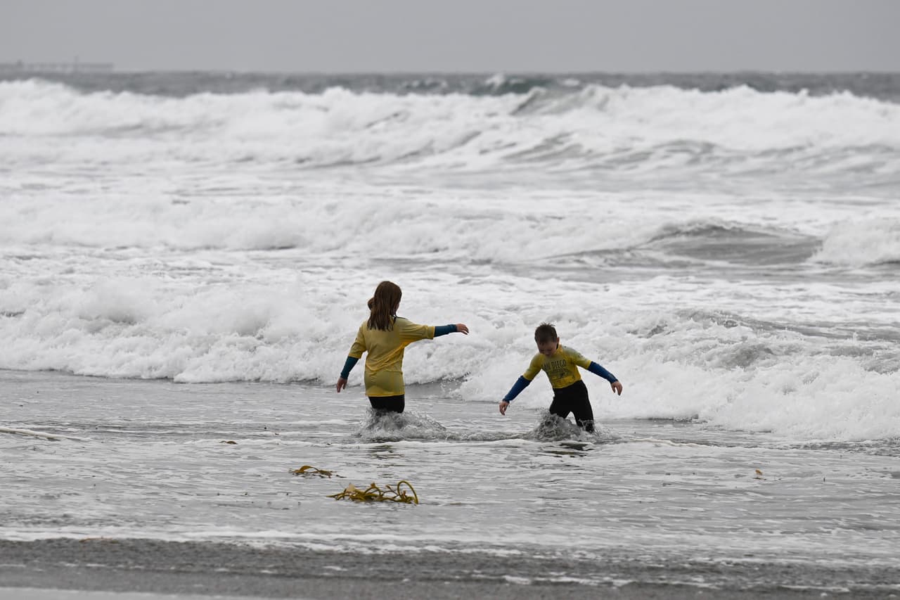 Niños juegan en el océano mientras el fuerte oleaje provocado por la tormenta azota San Diego el domingo 11 de octubre de 2026.