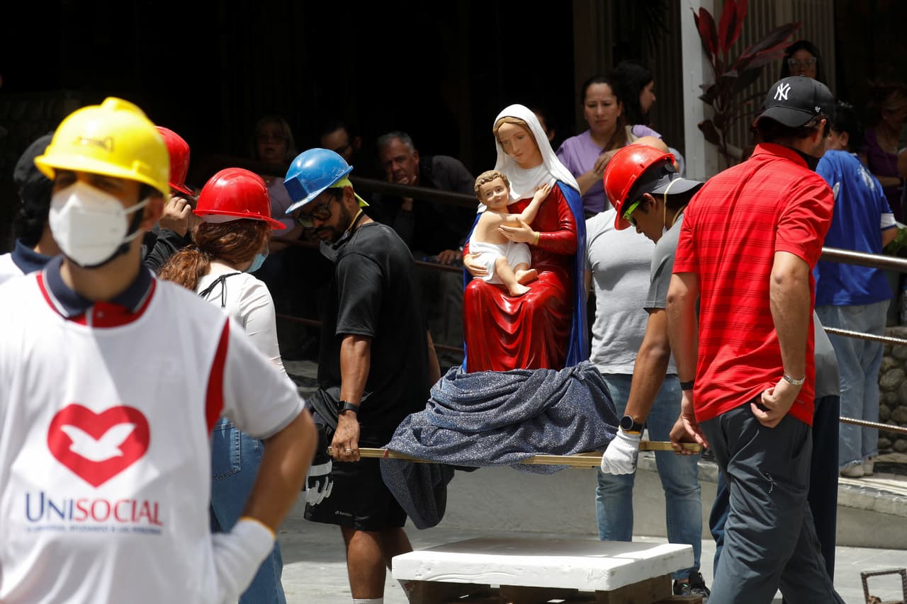 Varias personas transportan una estatua religiosa de la Virgen con el Niño cerca del lugar donde se encontraba un edificio dañado tras los terremotos que azotaron el país, en Caracas, Venezuela, el 25 de junio de 2026.