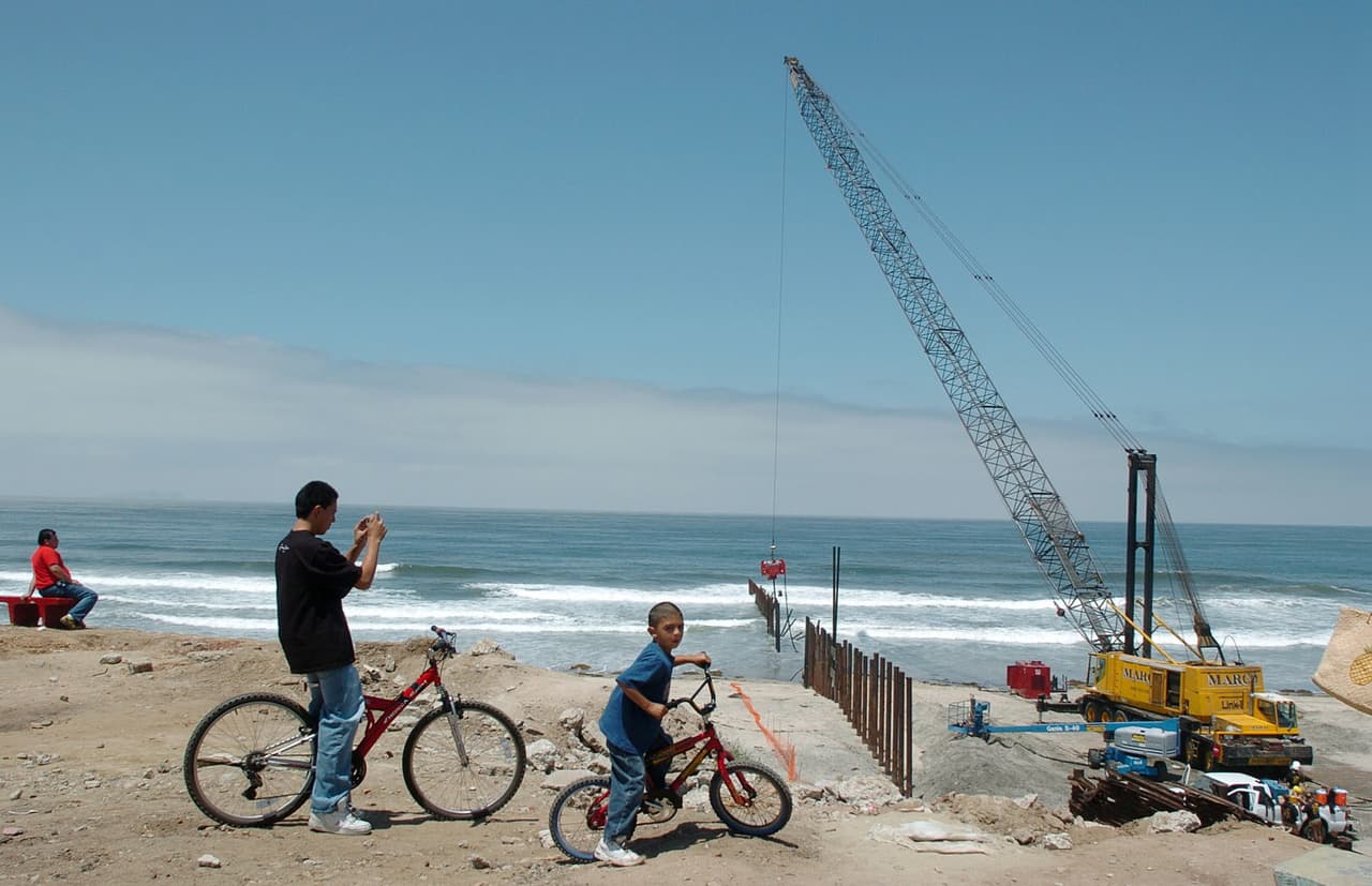 Algunos residentes de Tijuana, México, miraban en 2005 la reconstrucción de una antigua sección de la valla que llega hasta el Océano Pacífico.