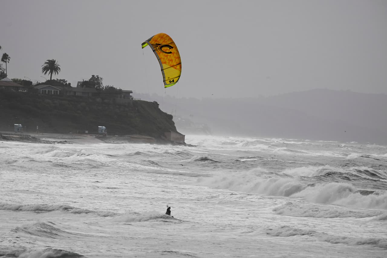 Un practicante de kitesurf navega entre el fuerte oleaje en la playa estatal de Cardiff, en Encinitas, California, el domingo 11 de octubre de 2026, debido a la tormenta tropical Rachel.