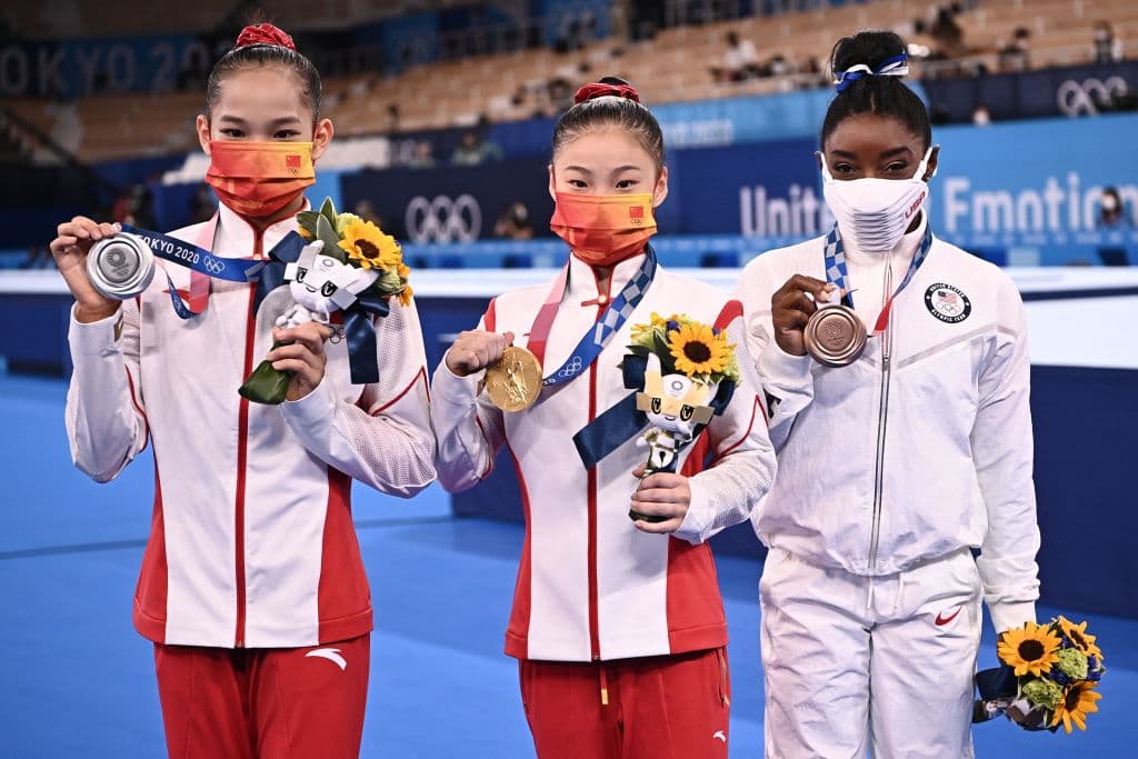 Las gimnasta chinas Xijing Tang (plata, a la izquierda) y Chenchen Guan (oro, al centro), compartiendo el podio con la estadounidense Simone Biles (bronce) en la competencia de barra de equilibrio, en Tokyo 2020.
