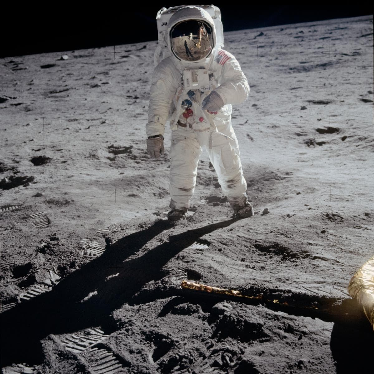 El 20 de julio de 1969, durante la misión Apolo 11, Buzz Aldrin camina sobre el Mar de la Tranquilidad cerca del módulo Eagle. Neil Armstrong capturó esta histórica imagen con una cámara de 70 mm, reflejándose en la visera de Aldrin. Mientras exploraban la superficie, Michael Collins aguardaba en órbita en los módulos de mando y servicio.