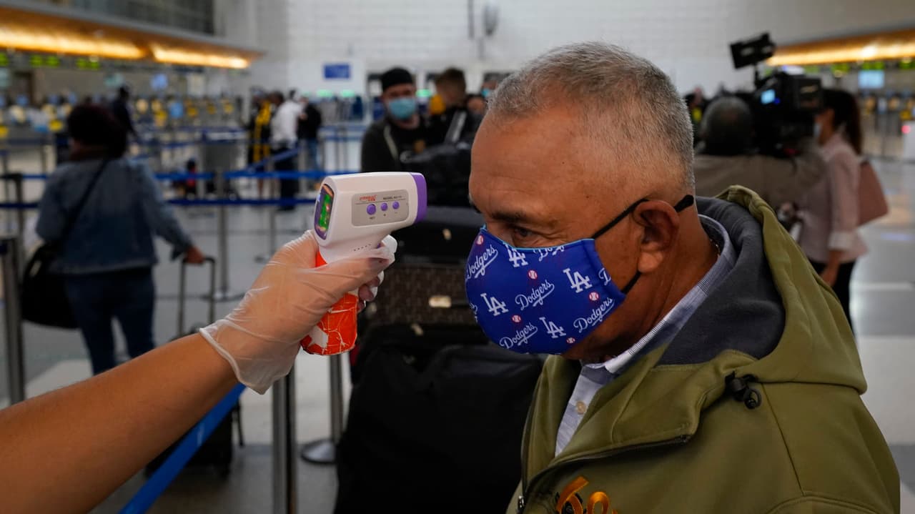 A un viajero le toman la temperatura el lunes mientras espera para registrarse en el Aeropuerto Internacional de Los Ángeles. Los estadounidenses llenaron los aeropuertos durante el fin de semana incluso cuando aumentaron los casos de coronavirus y los expertos en salud pública instaron a las personas a quedarse en casa.