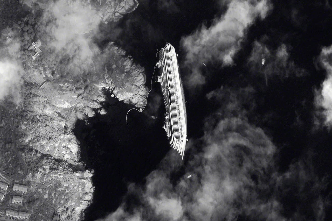 Una fotografía satelital del Costa Concordia encallado, tomada el 17 de enero de 2012. El pequeño pueblo se mantuvo con el casco del crucero a medio hundir frente a la costa durante casi dos años.