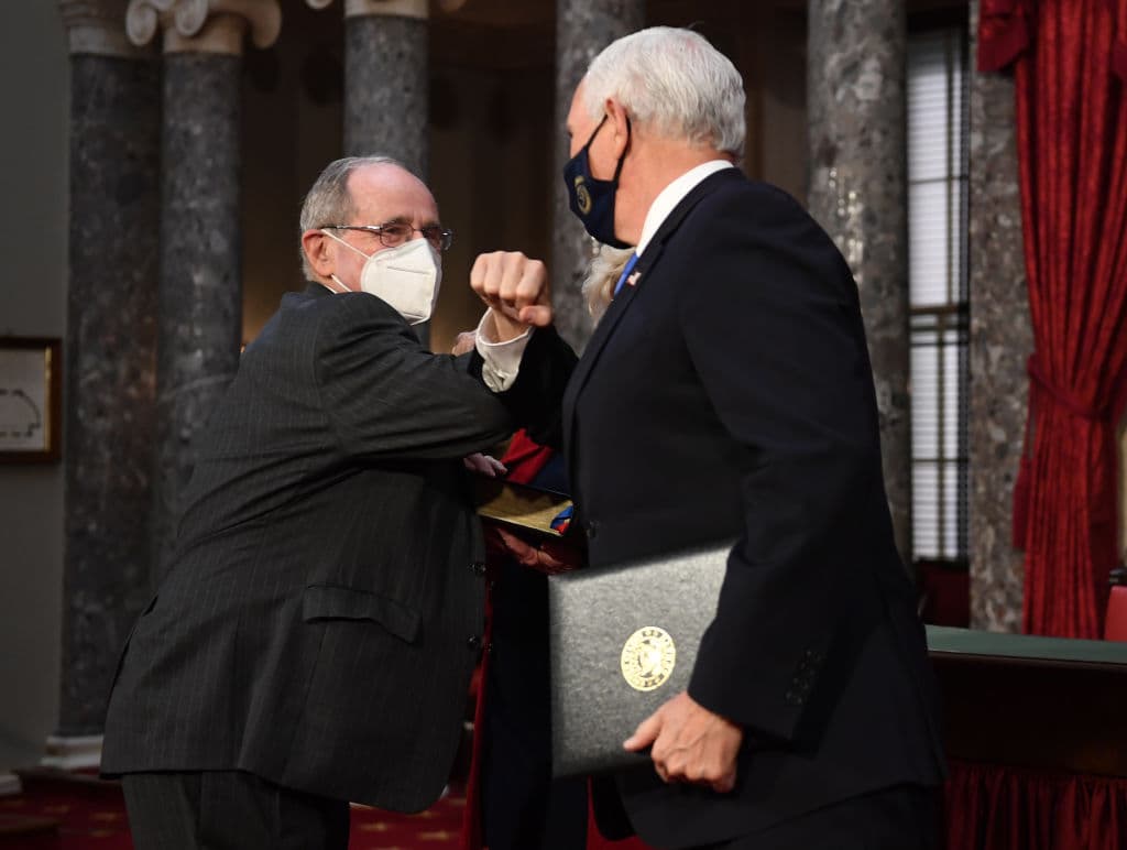 El vicepresidente Mike Pence y el senador republicano por Idaho James Risch se "dan el codo", tras la juramentación en el primer día del nuevo Senado.