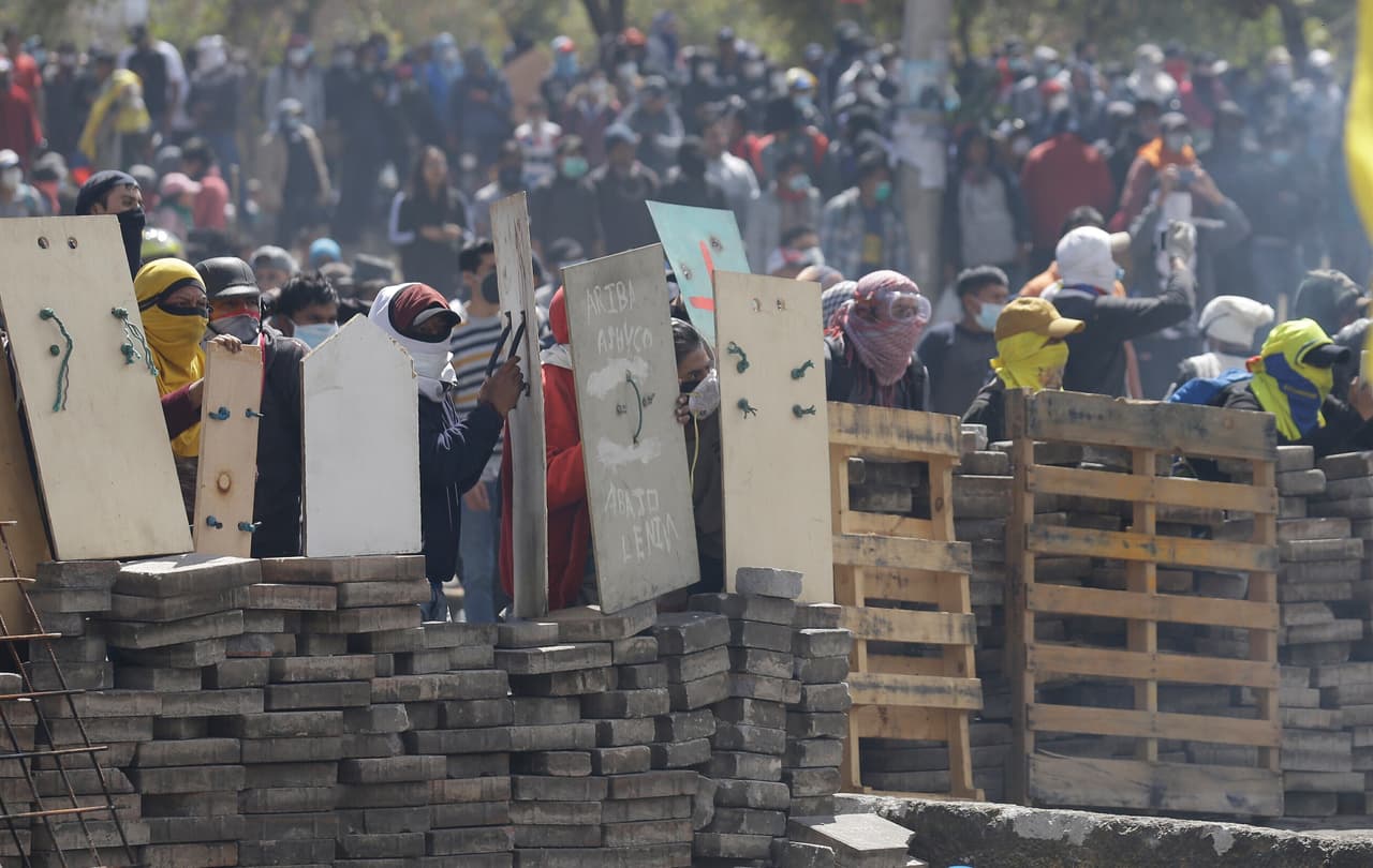 Manifestantes contrarios al gobierno se cubren tras una barricada en choques con la policía en Quito, Ecuador el 12 de octubre de 2019. (AP Foto/Fernando Vergara)