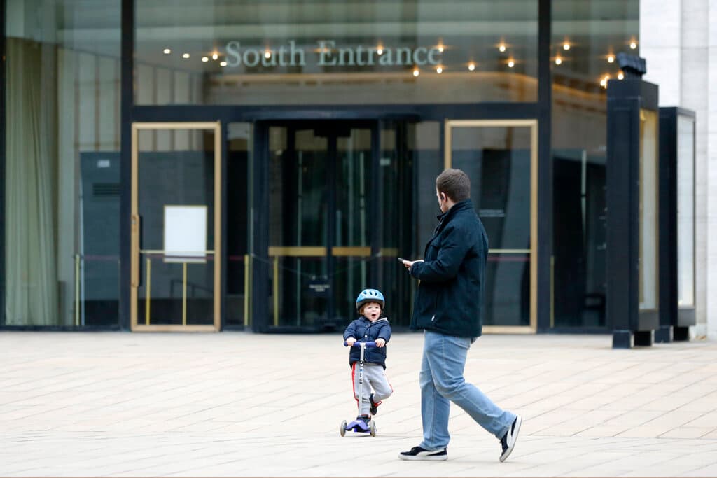 Un joven en patinete sorprende a un transeúnte mientras recorre la plaza casi vacía frente a la Metropolitan Opera del Lincoln Center, el jueves 12 de marzo de 2020, en Nueva York.