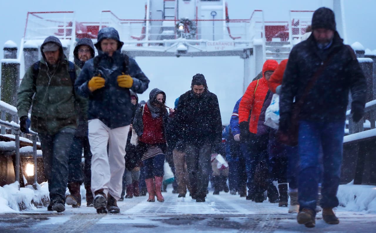 Los pasajeros que bajaron de un ferry caminan por una tormenta de nieve en Portland, Maine.