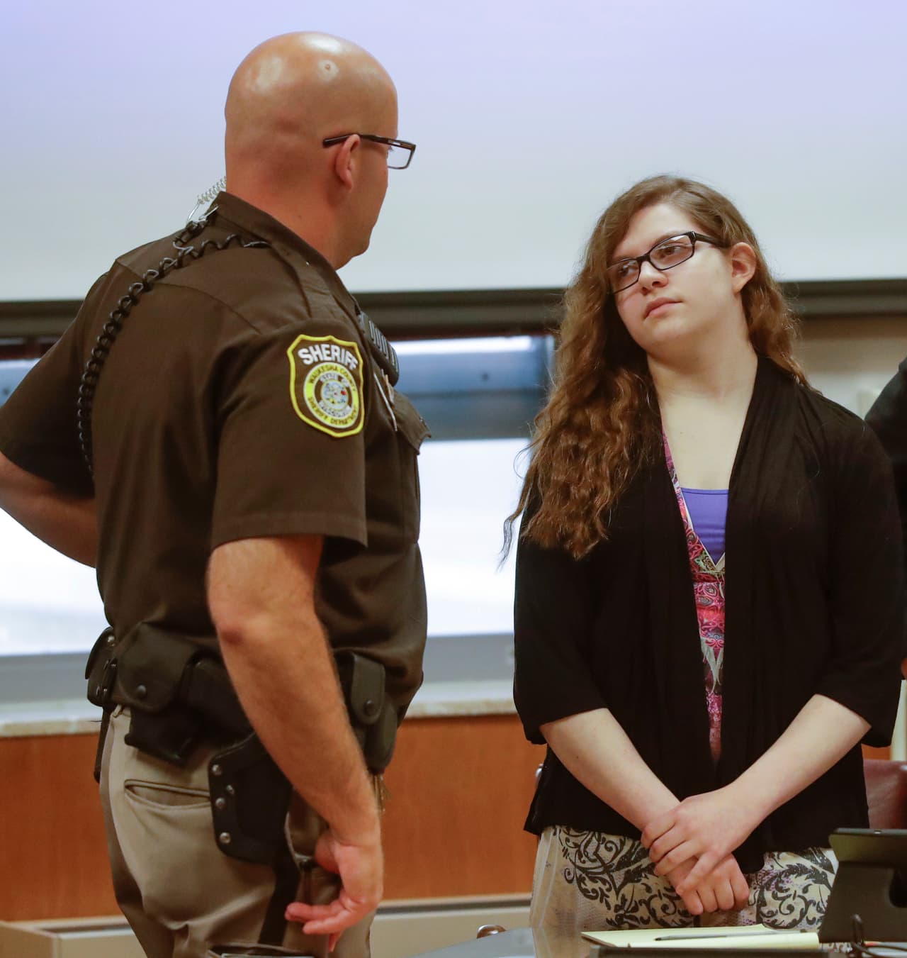Anissa Weier talks to a sheriff's deputy during a pause in jury selection in the trial to determine 15-year-old Weier's competency at Waukesha County Courthouse Monday, Sept 11, 2017, in Waukesha, Wis. Prosecutors allege that Weier and her friend, Morgan Geyser, lured classmate Payton Leutner into a Waukesha park in May 2014 and stabbed her 19 times. The girls have said it was an effort to please a fictional horror character known as Slender Man. (AP Photo/Morry Gash, Pool)