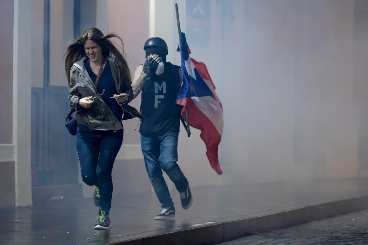 Manifestantes corren para protegerse del humo de los gases.