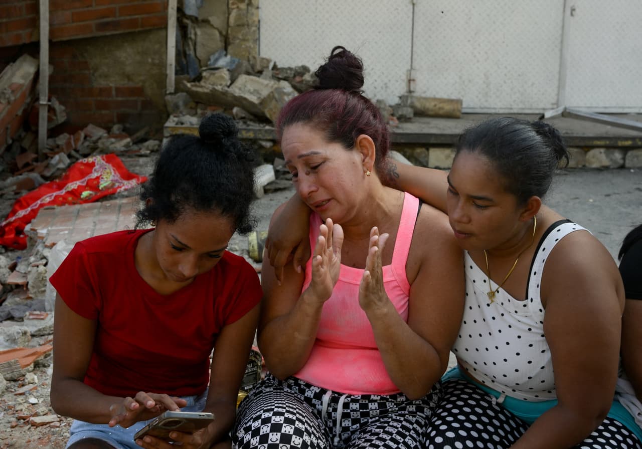 Varias personas se sientan junto a los escombros de edificios dañados tras los terremotos en La Guaira, Venezuela, el 25 de junio de 2026.