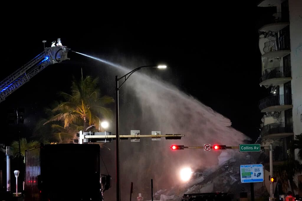 Un equipo de bomberos de Miami-Dade rocía agua sobre los escombros mientras continúan los esfuerzos de rescate donde se derrumbó un ala de un edificio de condominios frente a la playa de 12 pisos, el jueves 24 de junio de 2021 en el área de Surfside de Miami.