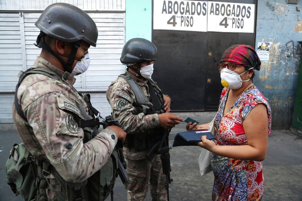 Una mujer explica a los soldados que está buscando alcohol en farmacias, antes de que la dejen continuar su camino, en el tercer día del estado de emergencia en Lima, Perú, el 18 de marzo de 2020.
