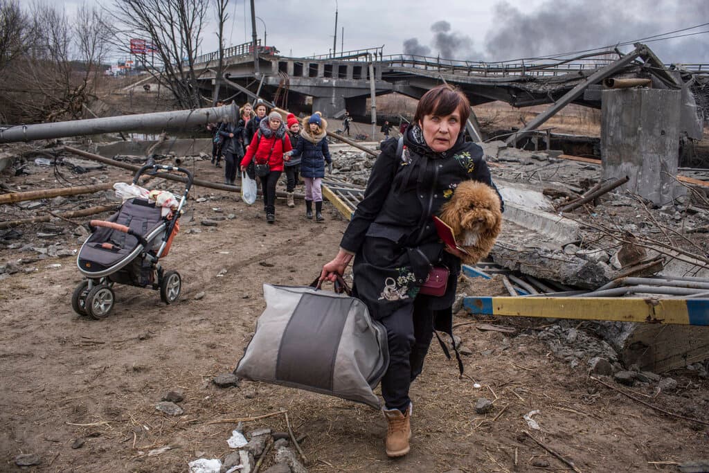 People cross an improvised path under a destroyed bridge while fleeing the town of Irpin, Ukraine, Sunday, March 6, 2022. In Irpin, near Kyiv, a sea of people on foot and even in wheelbarrows trudged over the remains of a destroyed bridge to cross a river and leave the city. (AP Photo/Oleksandr Ratushniak)