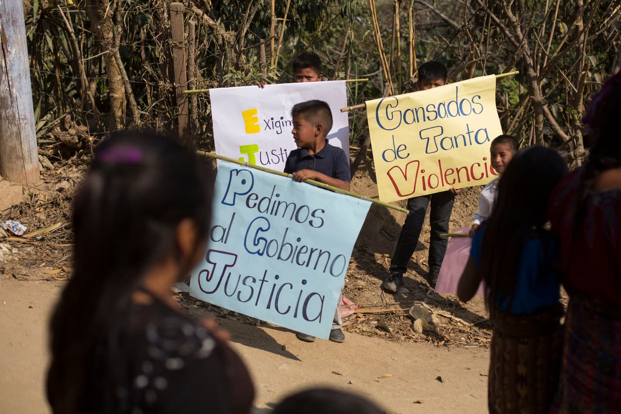 Los niños sostienen carteles con mensajes que se leen en español: "Exigimos justicia del gobierno" y "Cansados de tanta violencia", durante los entierros de Carlos Daniel Xiquin, de 10 años, y Oscar Armando Toc Cotzajay, de 11, que fueron secuestrados y luego asesinados en Ajuix, Guatemala, el martes 14 de febrero de 2017.
