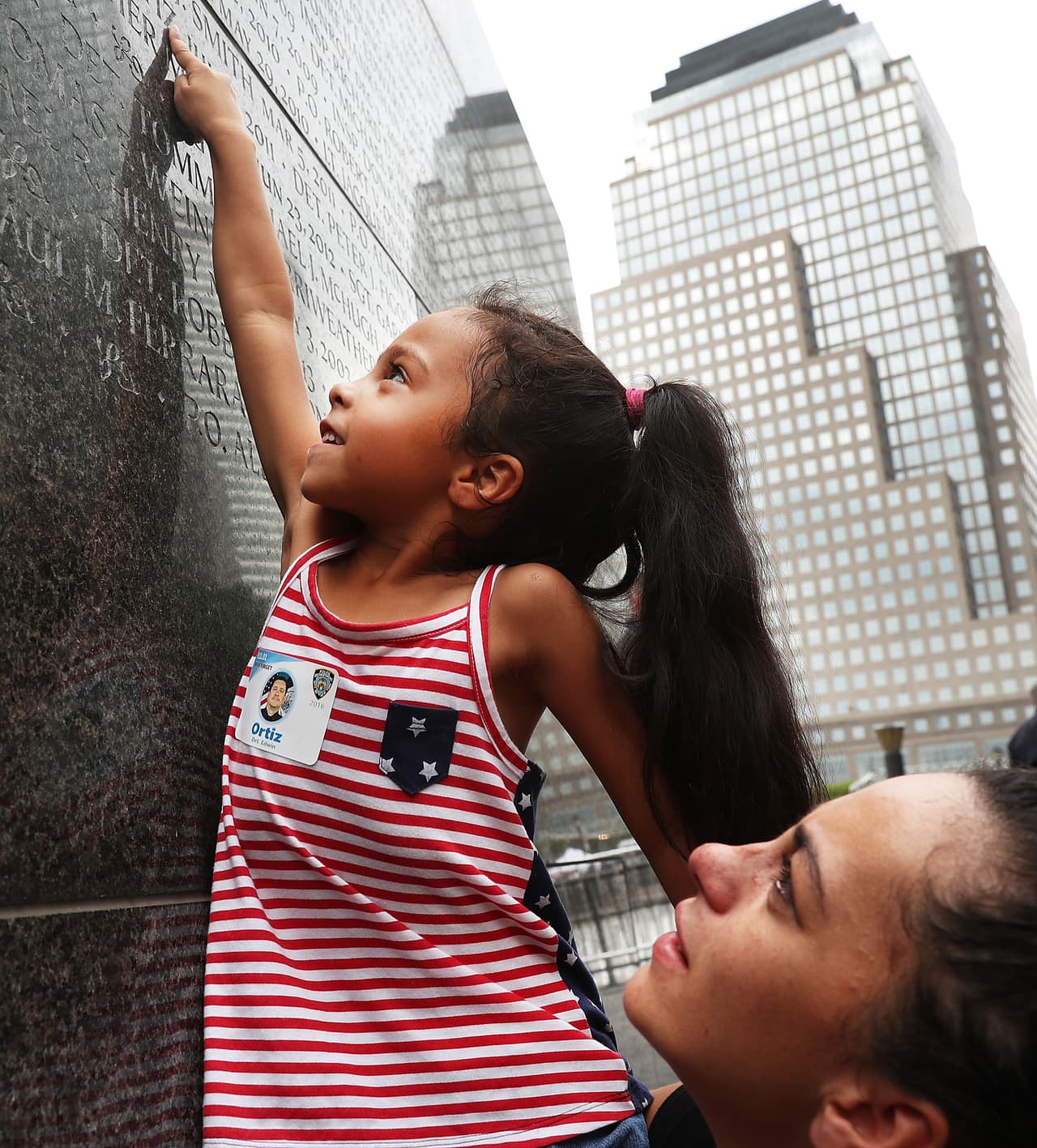 Adriana sonríe al encontrar el nombre de su abuelo, el oficial Edwin Rodríguez, en el mural que destaca a los miembros del NYPD que dieron su vida y su salud por salvar al prójimo.
